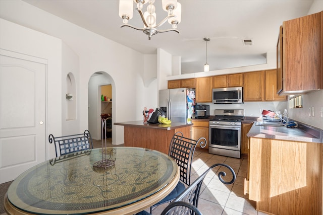 kitchen featuring visible vents, brown cabinetry, a kitchen island, appliances with stainless steel finishes, and a sink