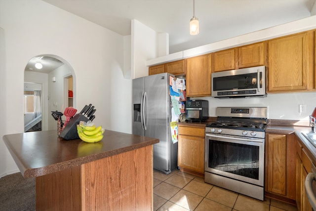 kitchen featuring stainless steel appliances, dark countertops, and arched walkways