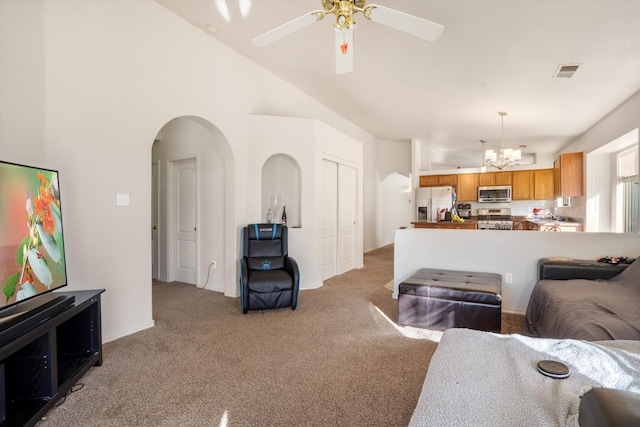 living area with light carpet, vaulted ceiling, visible vents, and arched walkways