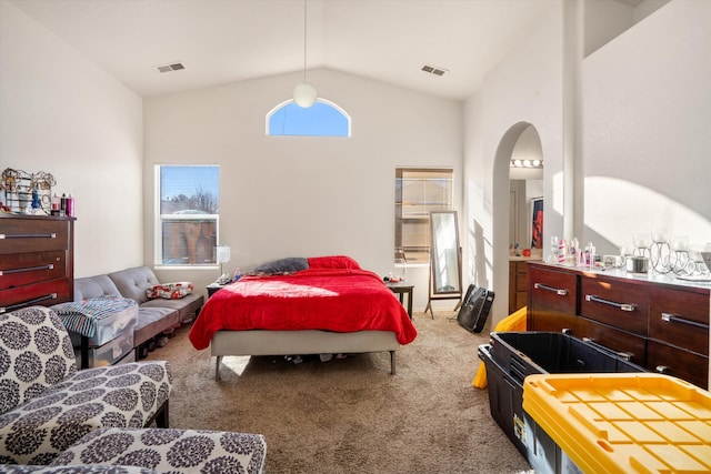 bedroom with lofted ceiling, carpet floors, arched walkways, and visible vents