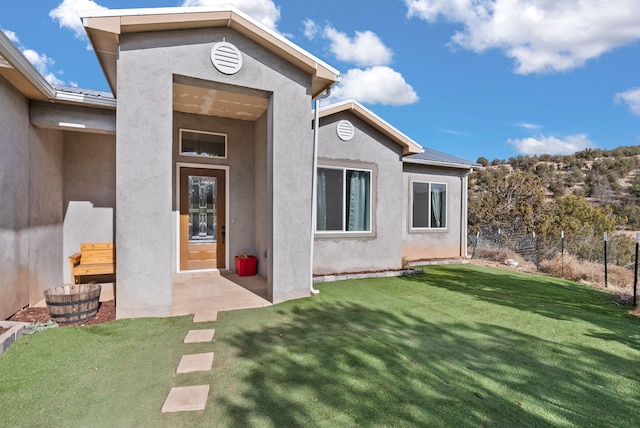 view of exterior entry featuring a lawn