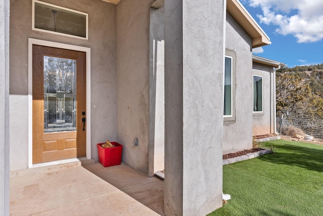 doorway to property featuring a lawn and a patio