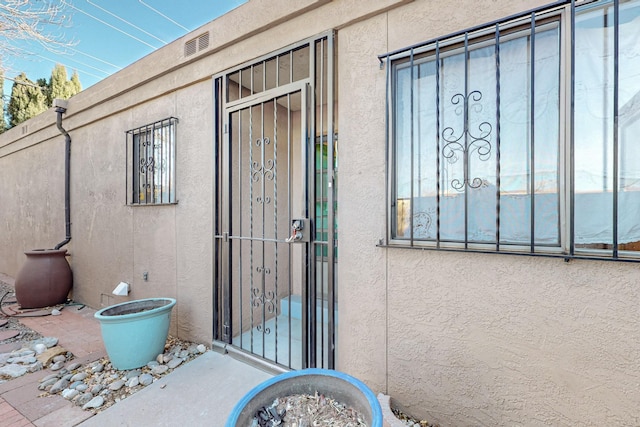 doorway to property featuring a gate and stucco siding