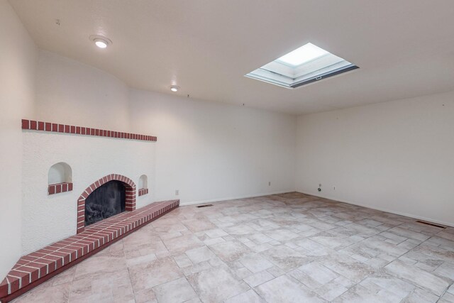 unfurnished living room featuring a skylight and a brick fireplace