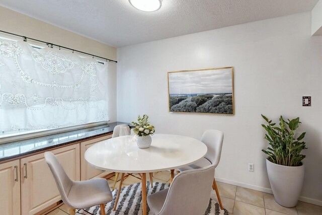 tiled dining space featuring a textured ceiling