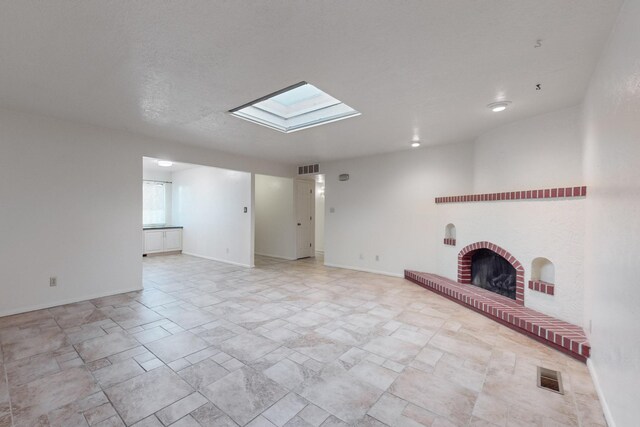 unfurnished living room featuring a skylight, a fireplace, and a textured ceiling