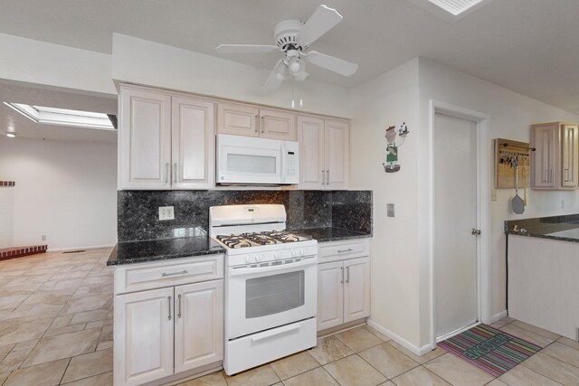 kitchen with ceiling fan, backsplash, dark stone counters, white appliances, and light tile patterned flooring