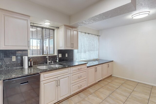 kitchen with sink, dark stone countertops, light tile patterned floors, black dishwasher, and tasteful backsplash