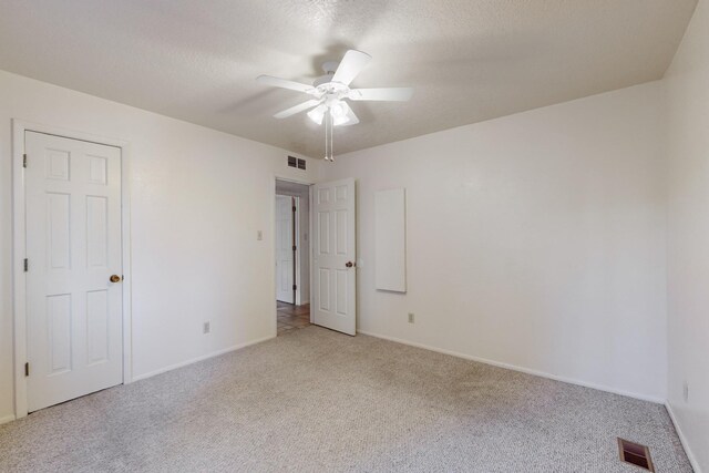 carpeted empty room featuring ceiling fan and a textured ceiling