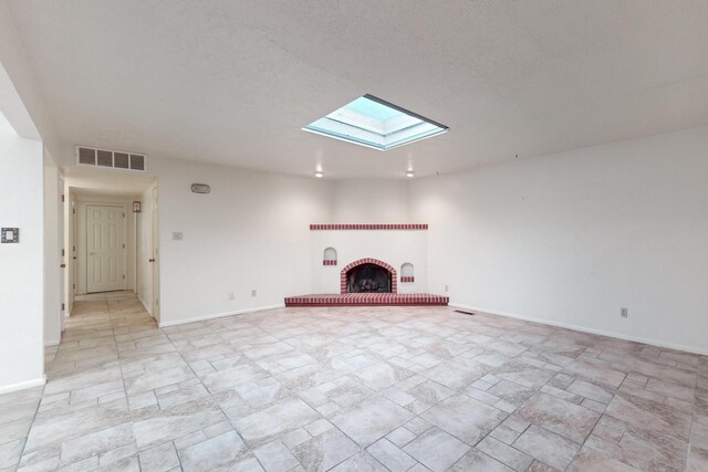 unfurnished living room featuring a skylight and a brick fireplace