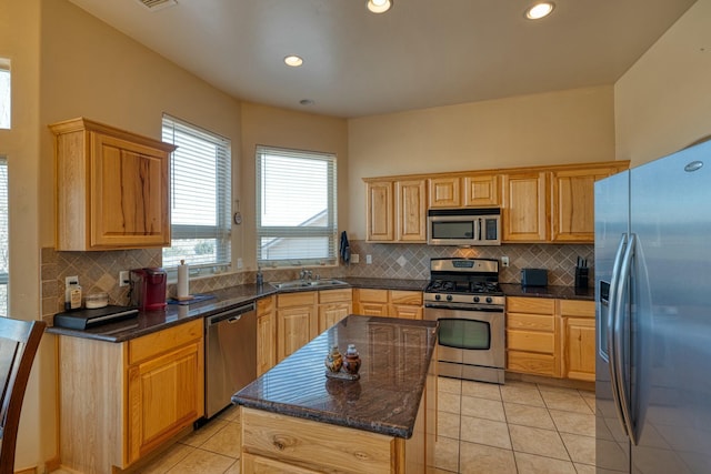 kitchen featuring sink, stainless steel appliances, a kitchen island, backsplash, and light tile patterned flooring