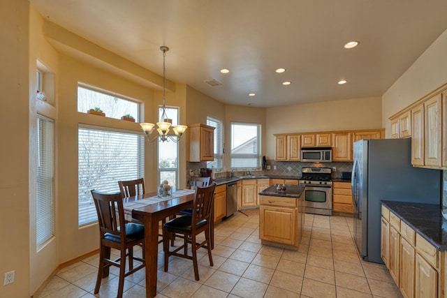 kitchen featuring tasteful backsplash, a notable chandelier, pendant lighting, a kitchen island, and appliances with stainless steel finishes