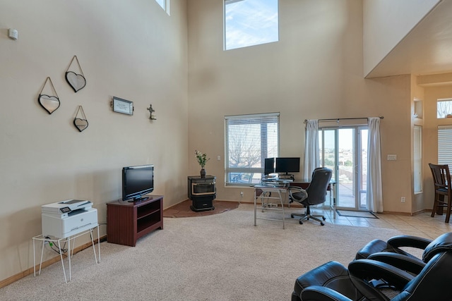 carpeted home office with a high ceiling and a wood stove