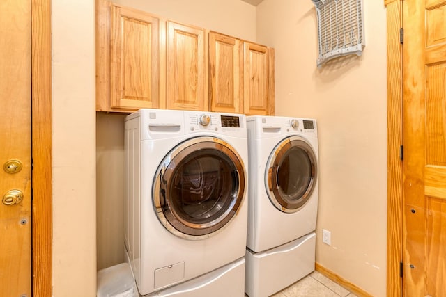 clothes washing area featuring washer and clothes dryer, light tile patterned floors, and cabinets