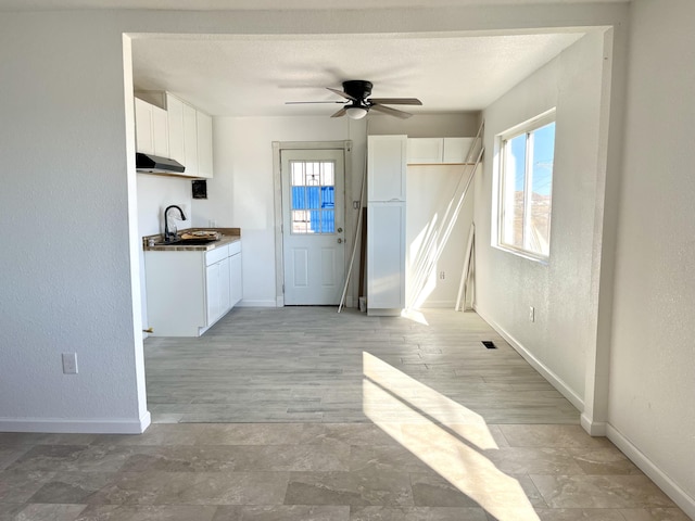 407 E Maloney Ave, Gallup, NM 87301 - kitchen with a ceiling fan, white cabinets, under cabinet range hood, and a textured wall
