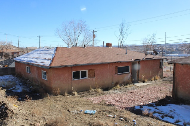 view of side of property with a shingled roof and stucco siding