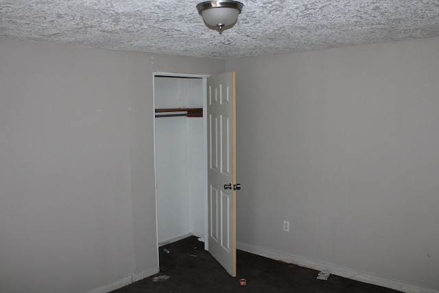 unfurnished bedroom with a closet, a textured ceiling, and baseboards