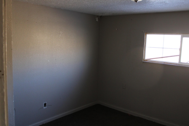 unfurnished room with baseboards and a textured ceiling