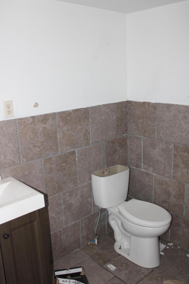 bathroom with toilet, tile walls, and vanity