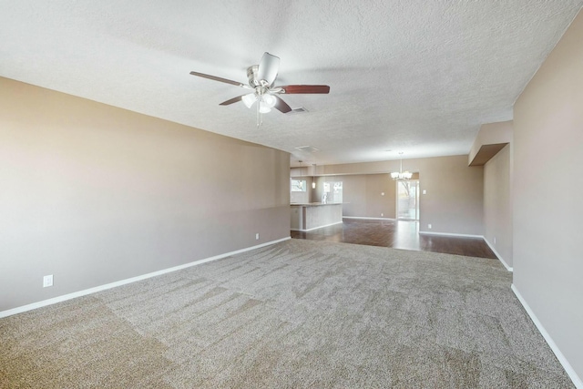 unfurnished living room with ceiling fan with notable chandelier, carpet floors, and a textured ceiling