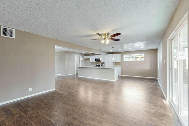 unfurnished living room featuring dark hardwood / wood-style flooring, a textured ceiling, ceiling fan, and sink