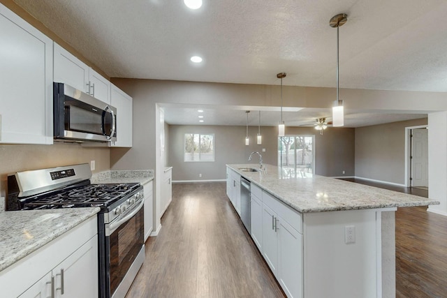 kitchen featuring white cabinets, sink, an island with sink, decorative light fixtures, and stainless steel appliances