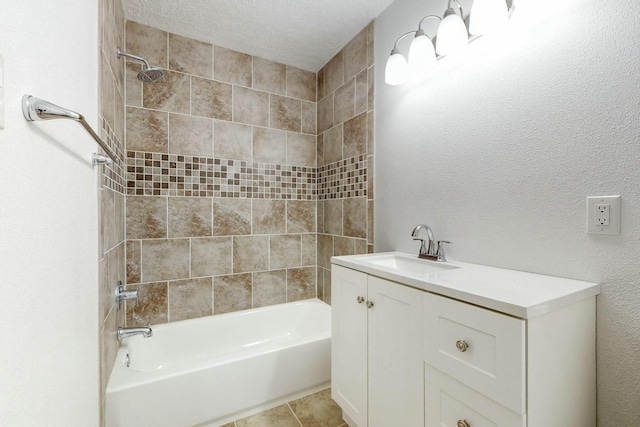 bathroom with a textured ceiling, vanity, and tiled shower / bath combo