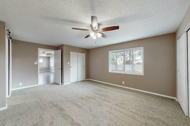 unfurnished bedroom featuring ceiling fan, light colored carpet, and two closets