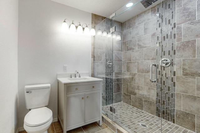 bathroom with tile patterned floors, vanity, toilet, and a shower with shower door