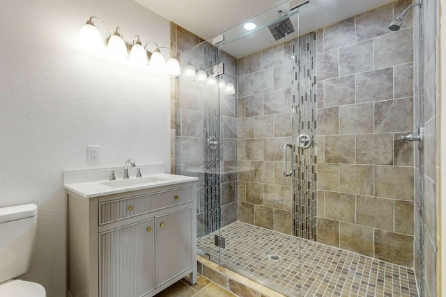 bathroom featuring tile patterned flooring, a shower with door, vanity, and toilet