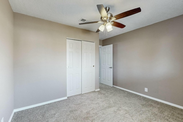 unfurnished bedroom with ceiling fan, a closet, carpet, and a textured ceiling