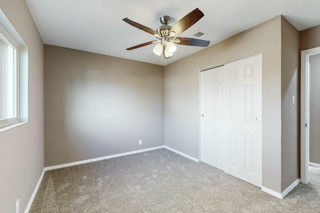 unfurnished bedroom featuring ceiling fan, light colored carpet, and a closet