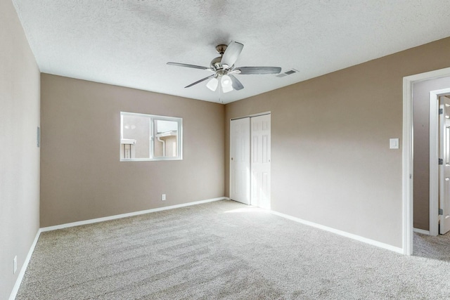 unfurnished bedroom featuring ceiling fan, a closet, light carpet, and a textured ceiling