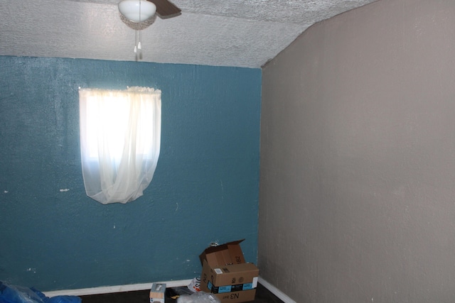 unfurnished room with a textured ceiling and lofted ceiling