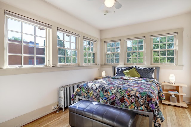 bedroom with ceiling fan, light hardwood / wood-style floors, and radiator heating unit