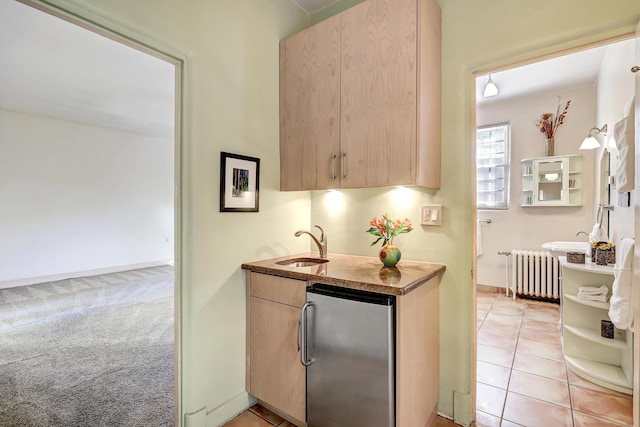 kitchen featuring radiator, light brown cabinetry, and refrigerator