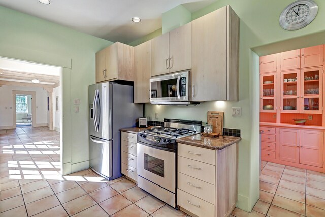 kitchen with light tile patterned floors, stainless steel appliances, and dark stone countertops