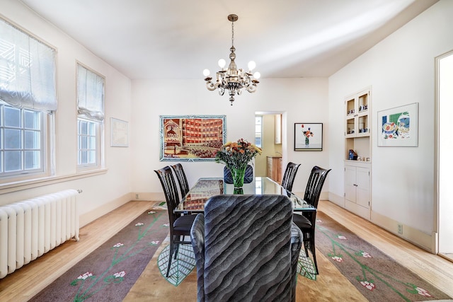 dining space with plenty of natural light, radiator, a chandelier, and light wood-type flooring