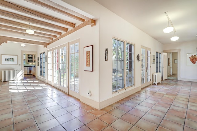 hallway featuring beam ceiling, radiator, and light tile patterned flooring