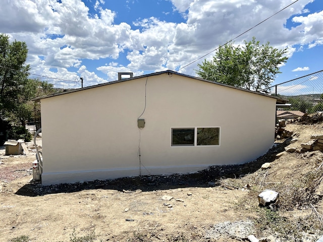 view of side of home featuring fence and stucco siding