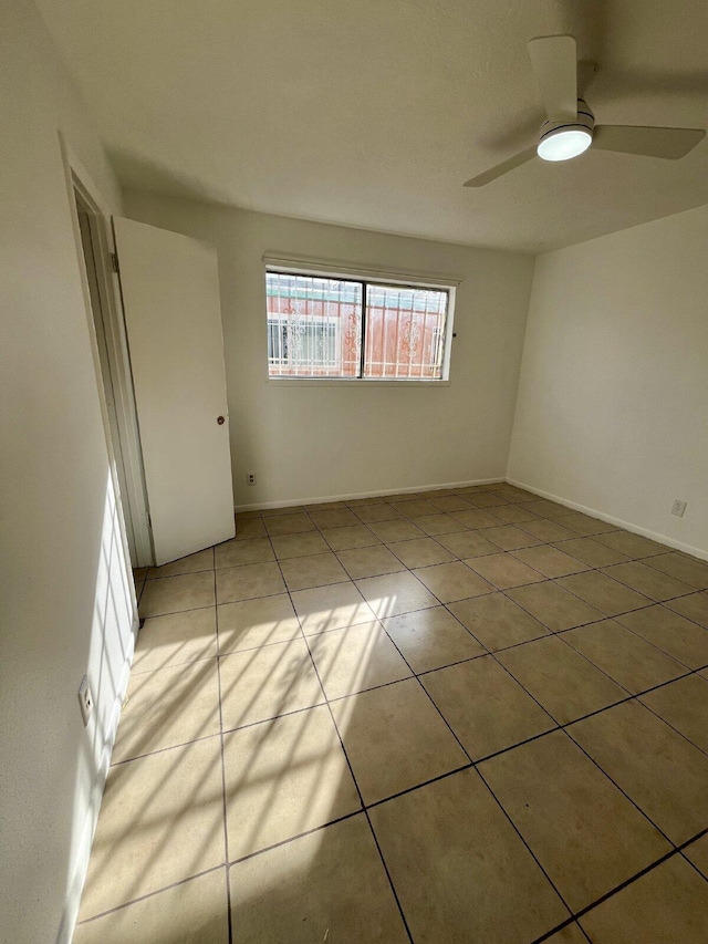 empty room featuring ceiling fan and light tile patterned flooring