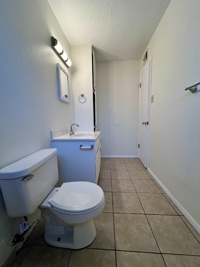 bathroom with tile patterned floors, vanity, a textured ceiling, and toilet