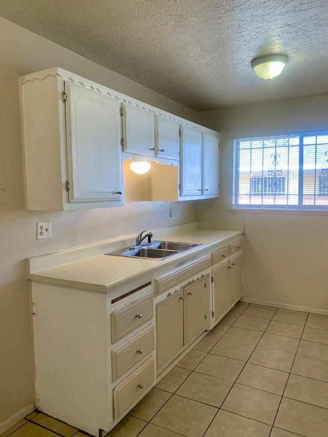 kitchen featuring white cabinets, a textured ceiling, light tile patterned flooring, and sink