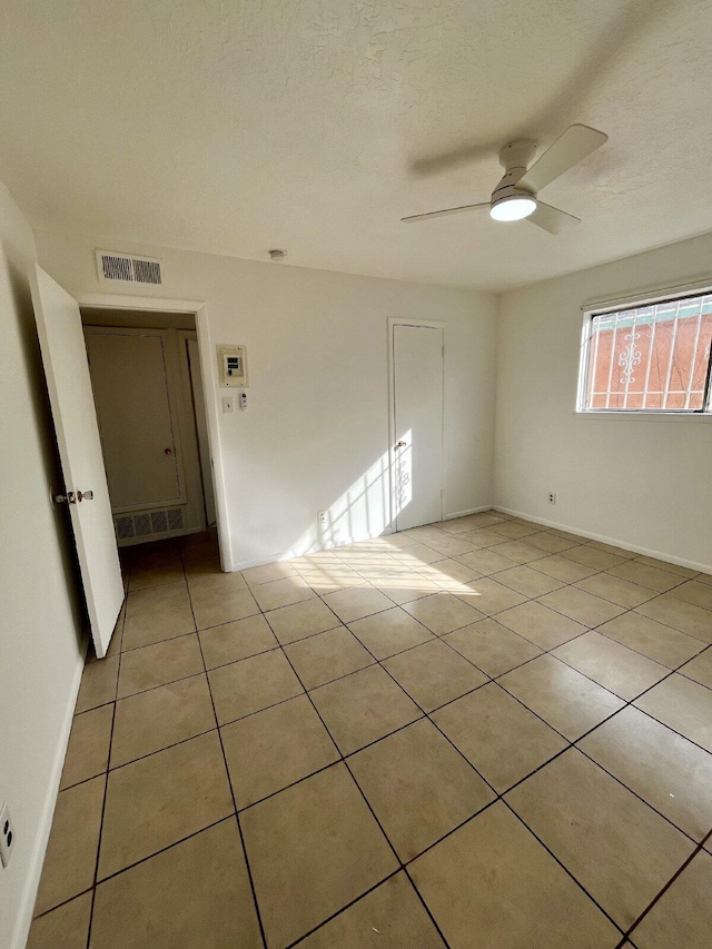 spare room with ceiling fan, light tile patterned floors, and a textured ceiling