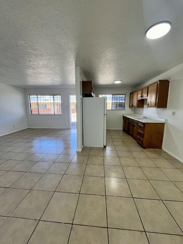 kitchen with light tile patterned floors, white fridge, and sink