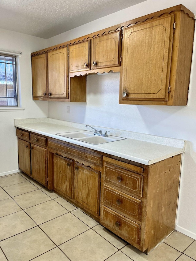 kitchen featuring sink, light tile patterned floors, and a textured ceiling