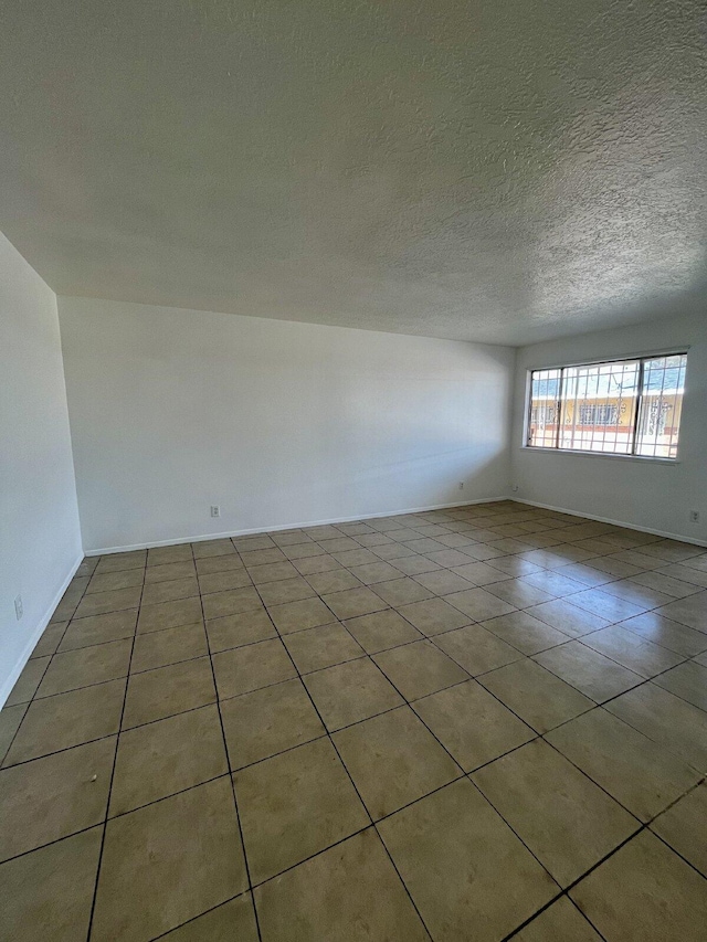 tiled empty room featuring a textured ceiling