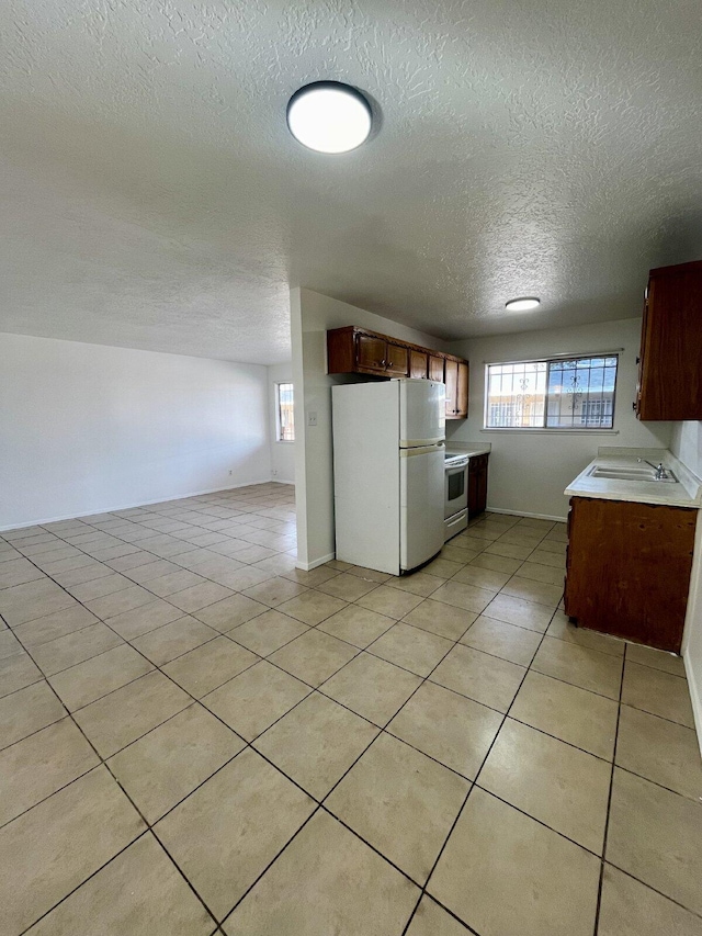 kitchen featuring a textured ceiling, light tile patterned floors, and white appliances