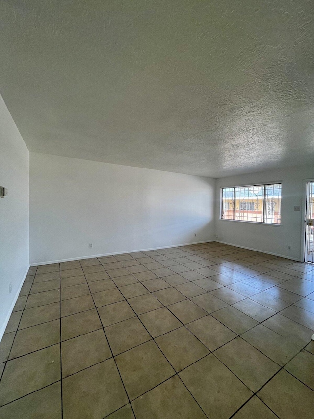 unfurnished room featuring light tile patterned flooring and a textured ceiling