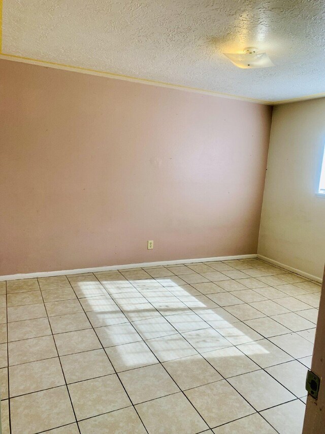 tiled spare room with a textured ceiling and crown molding